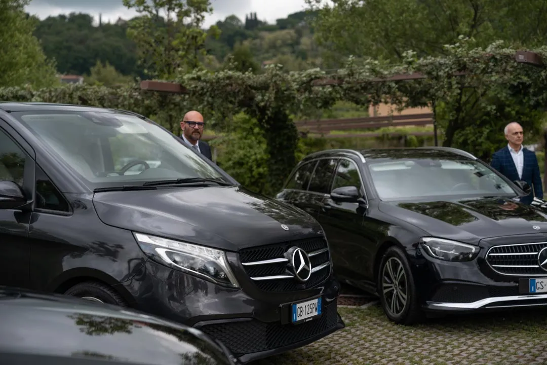 Due autisti Elite accanto a un Mercedes Classe V e a una station wagon